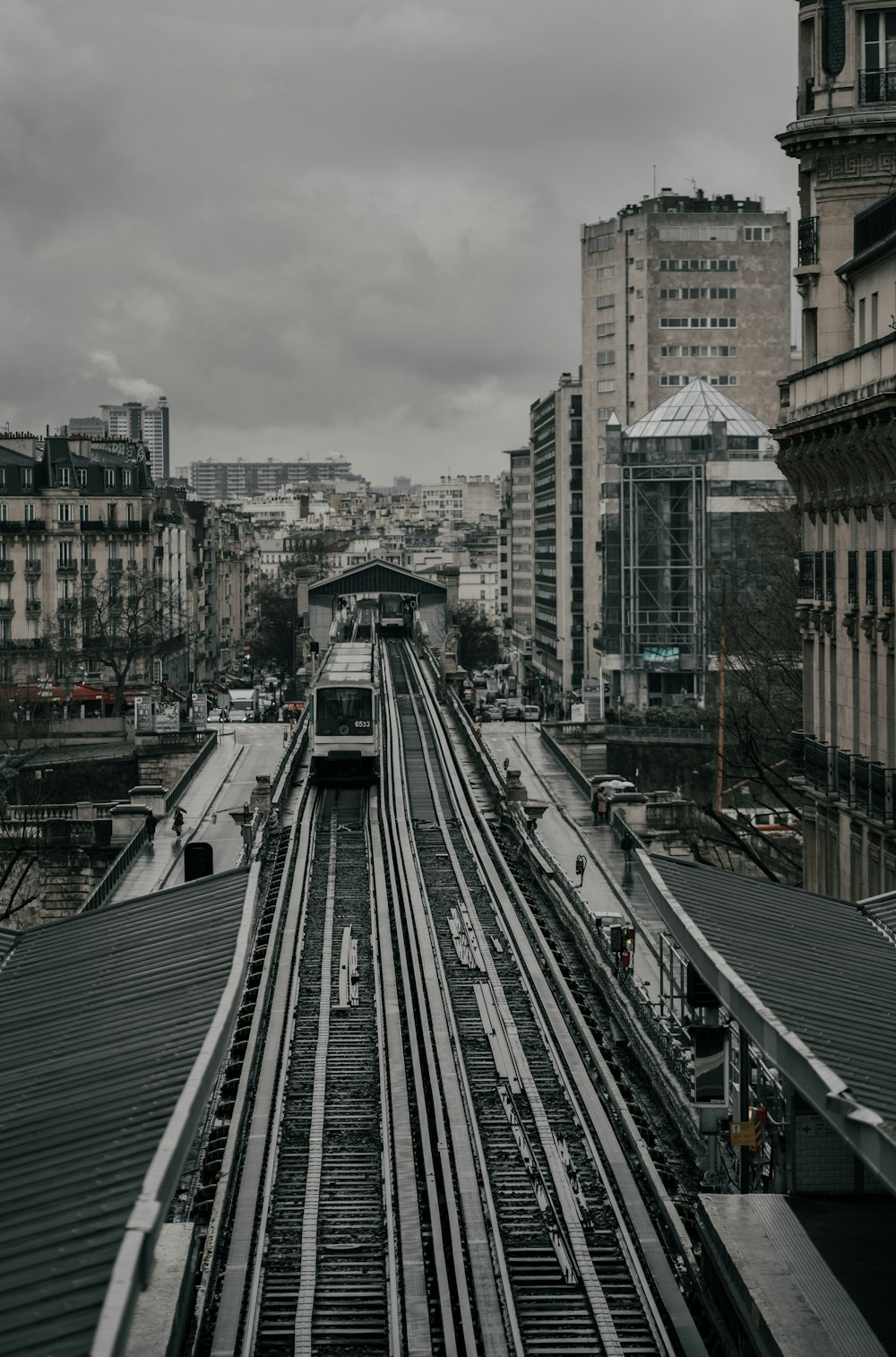 gray train rail near city buildings during daytime