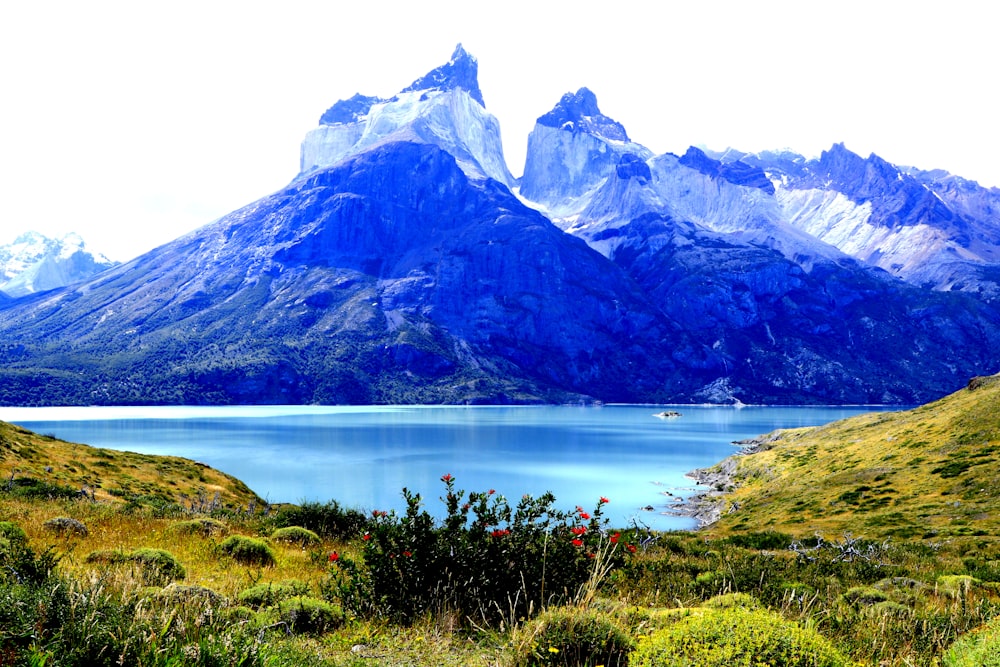 blue lake near green grass and mountain during daytime