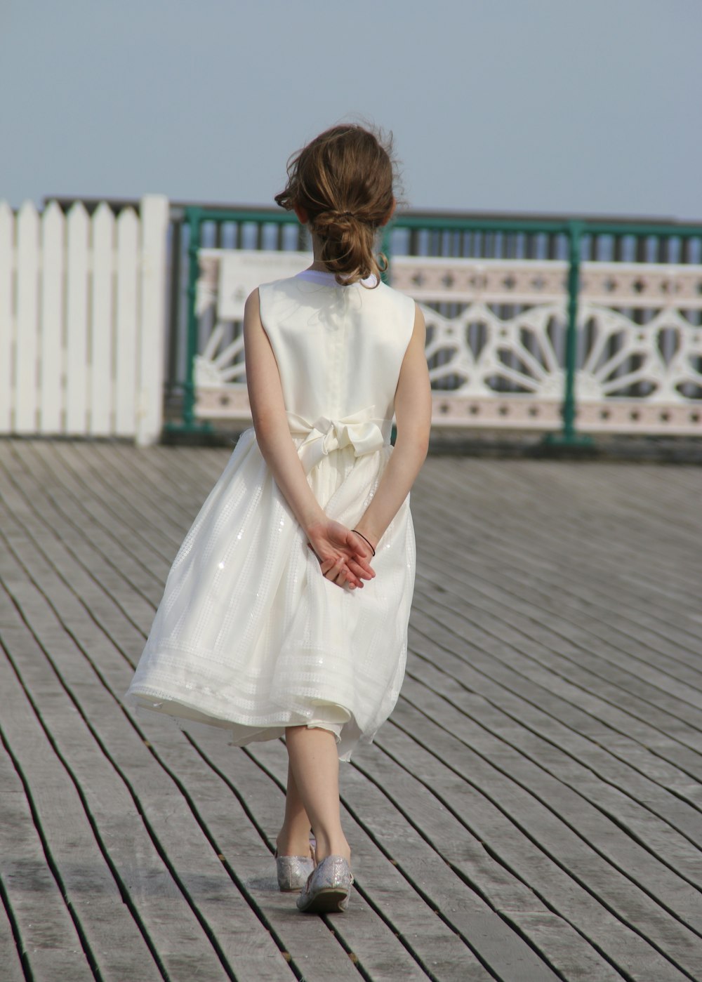 Frau in weißem ärmellosem Kleid tagsüber auf grauem Holzboden stehend