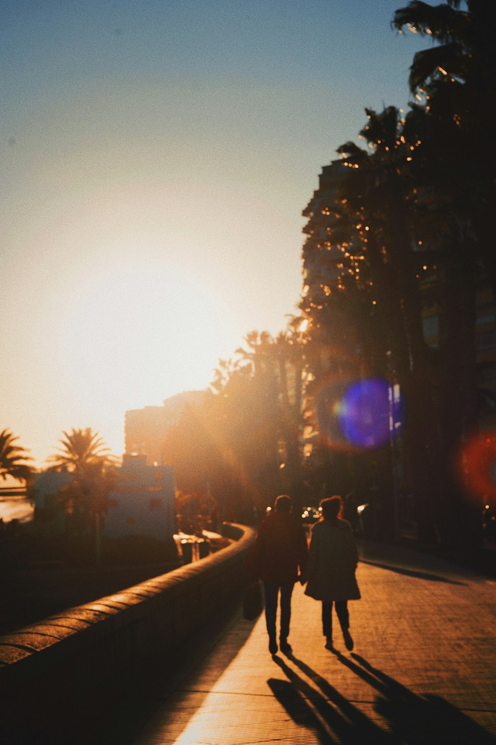 personnes marchant sur le trottoir au coucher du soleil