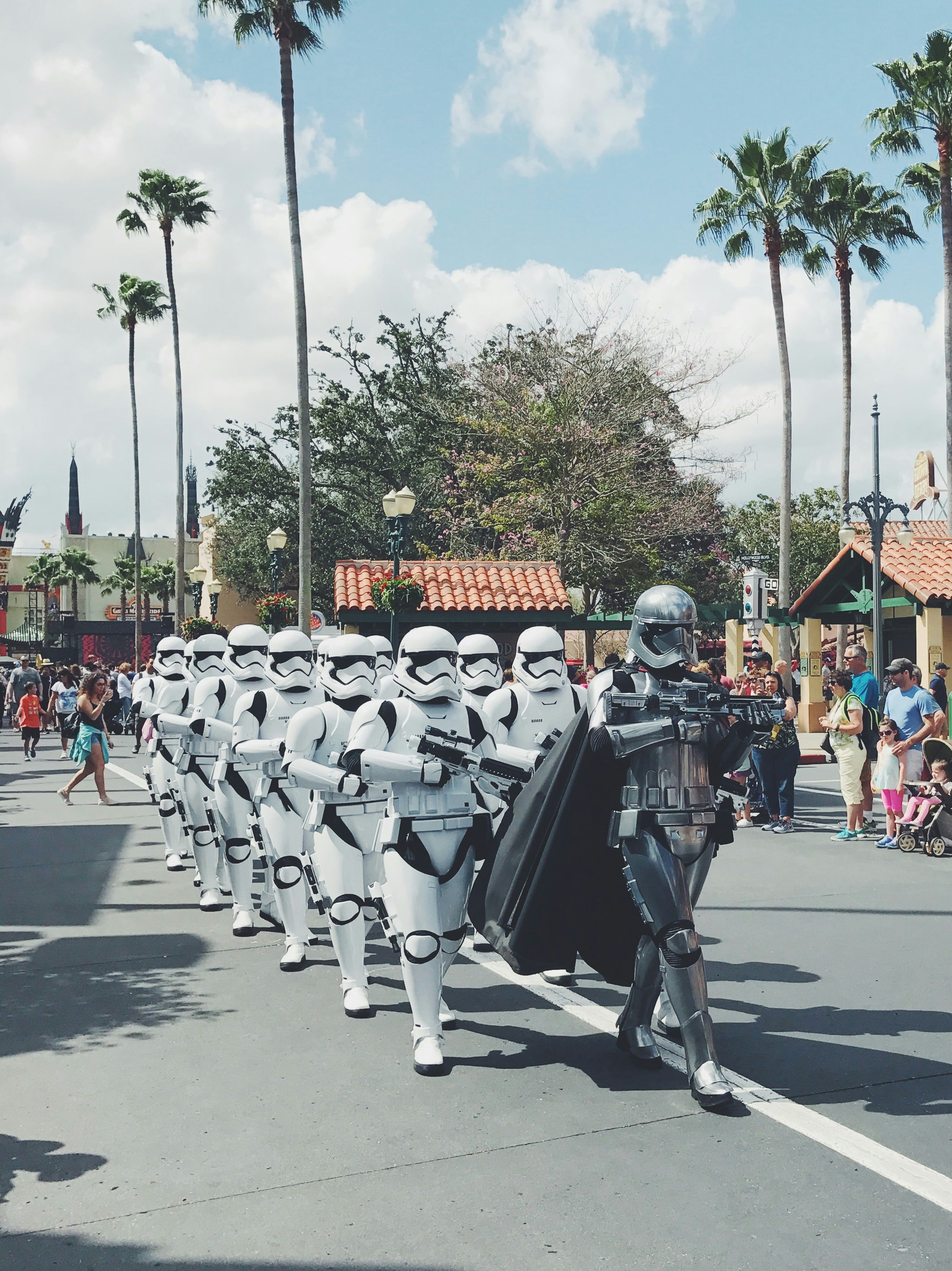 Orang-orang berjas hitam dan abu-abu mengendarai sepeda motor di siang hari