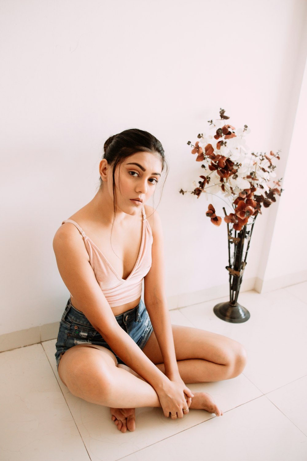 woman in brown tank top and blue denim shorts sitting on white ceramic toilet bowl