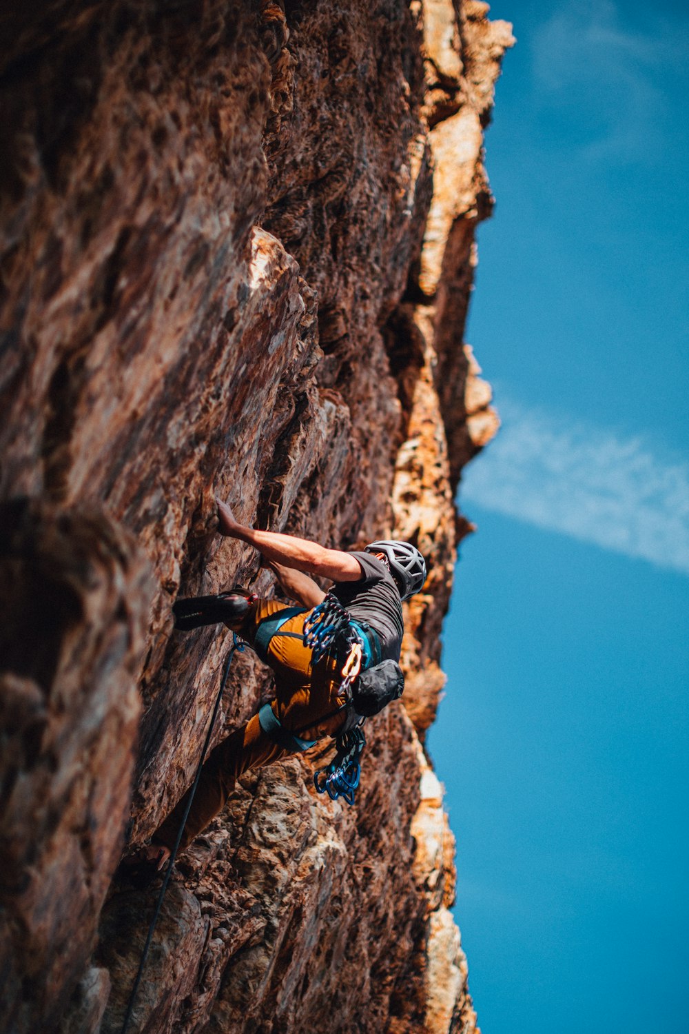 Uomo in pantaloncini neri che si arrampica sulla montagna rocciosa marrone durante il giorno