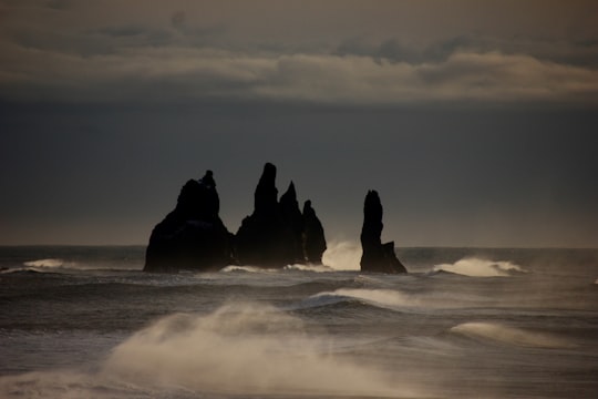 silhouette of rock formation on sea under gray clouds in Reynisdrangar Iceland