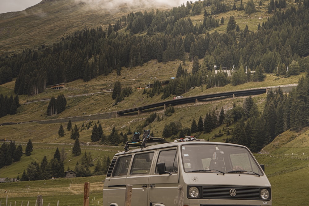 white and brown van on green grass field near green trees and mountain during daytime