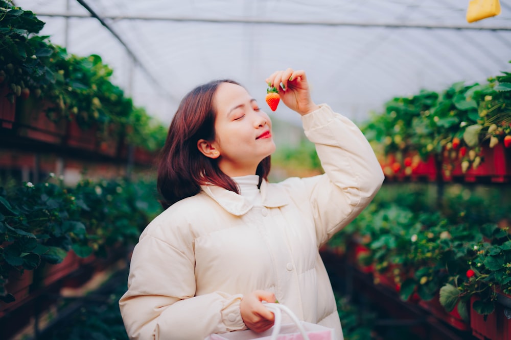 woman in white long sleeve shirt holding red flower