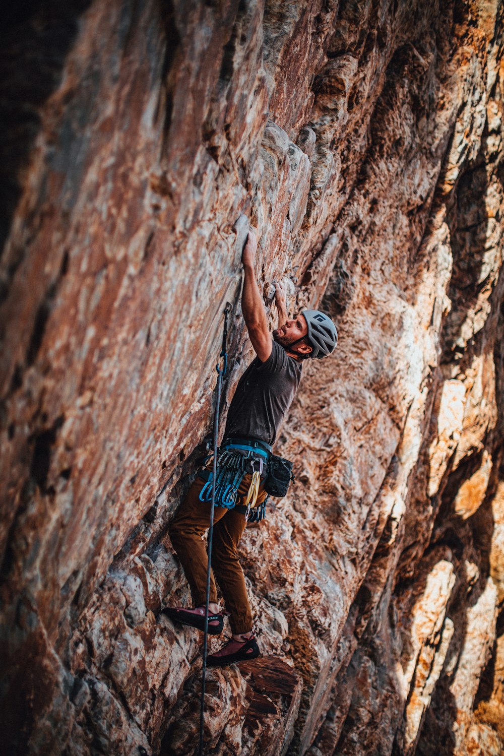 man in blue t-shirt and black shorts climbing brown rock mountain during daytime