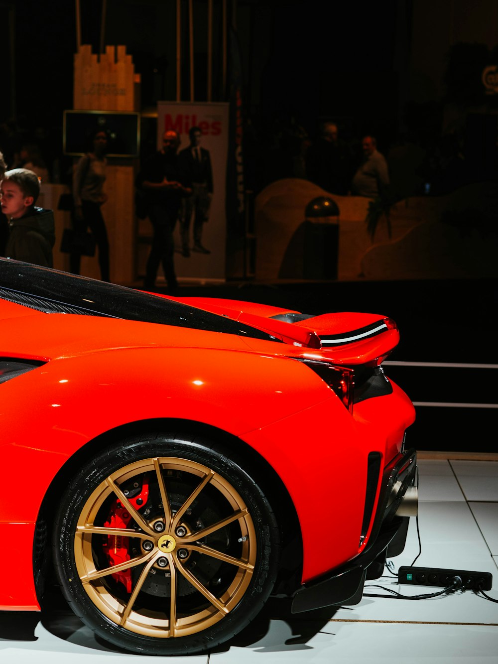 red ferrari car in front of people walking on street