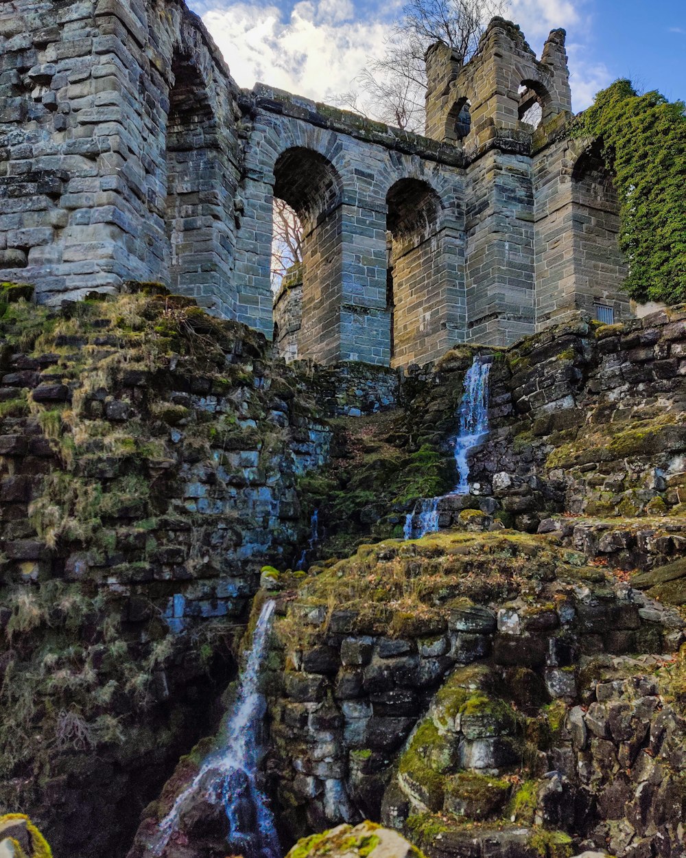 eine große Steinbrücke über einen kleinen Wasserfall