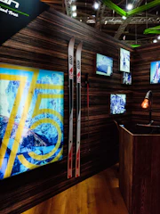 A cozy ski shop interior with neatly arranged skis, tuning tools, and friendly staff ready to assist customers.