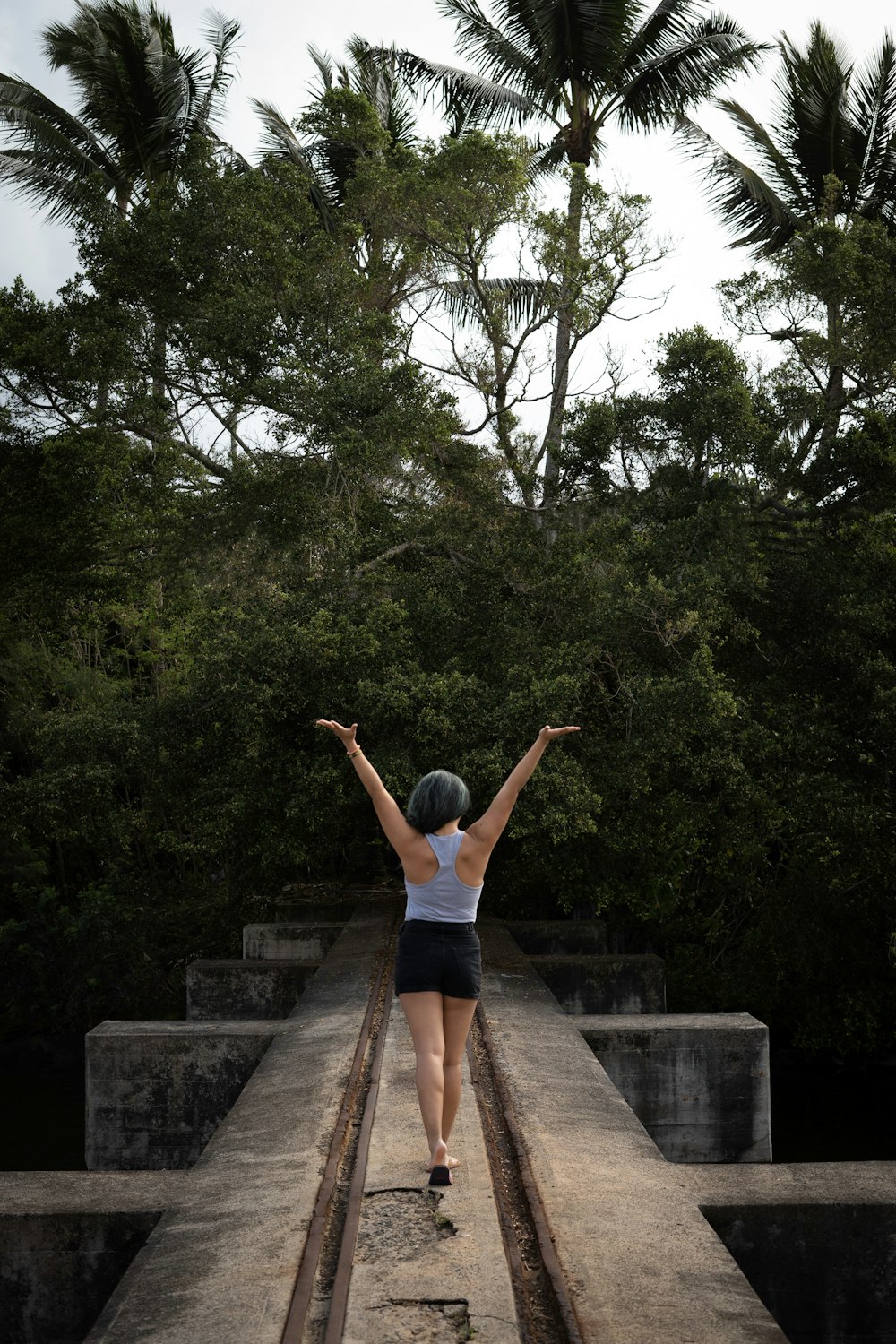 mulher na regata azul e shorts jeans azuis em pé nas escadas de concreto