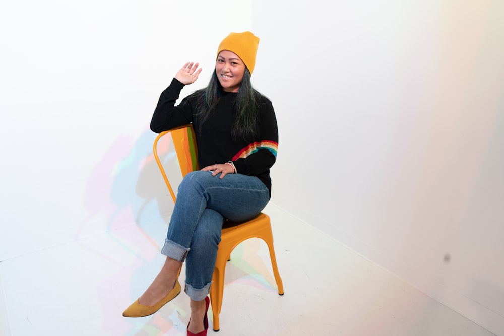 woman in black jacket and blue denim jeans sitting on brown wooden chair