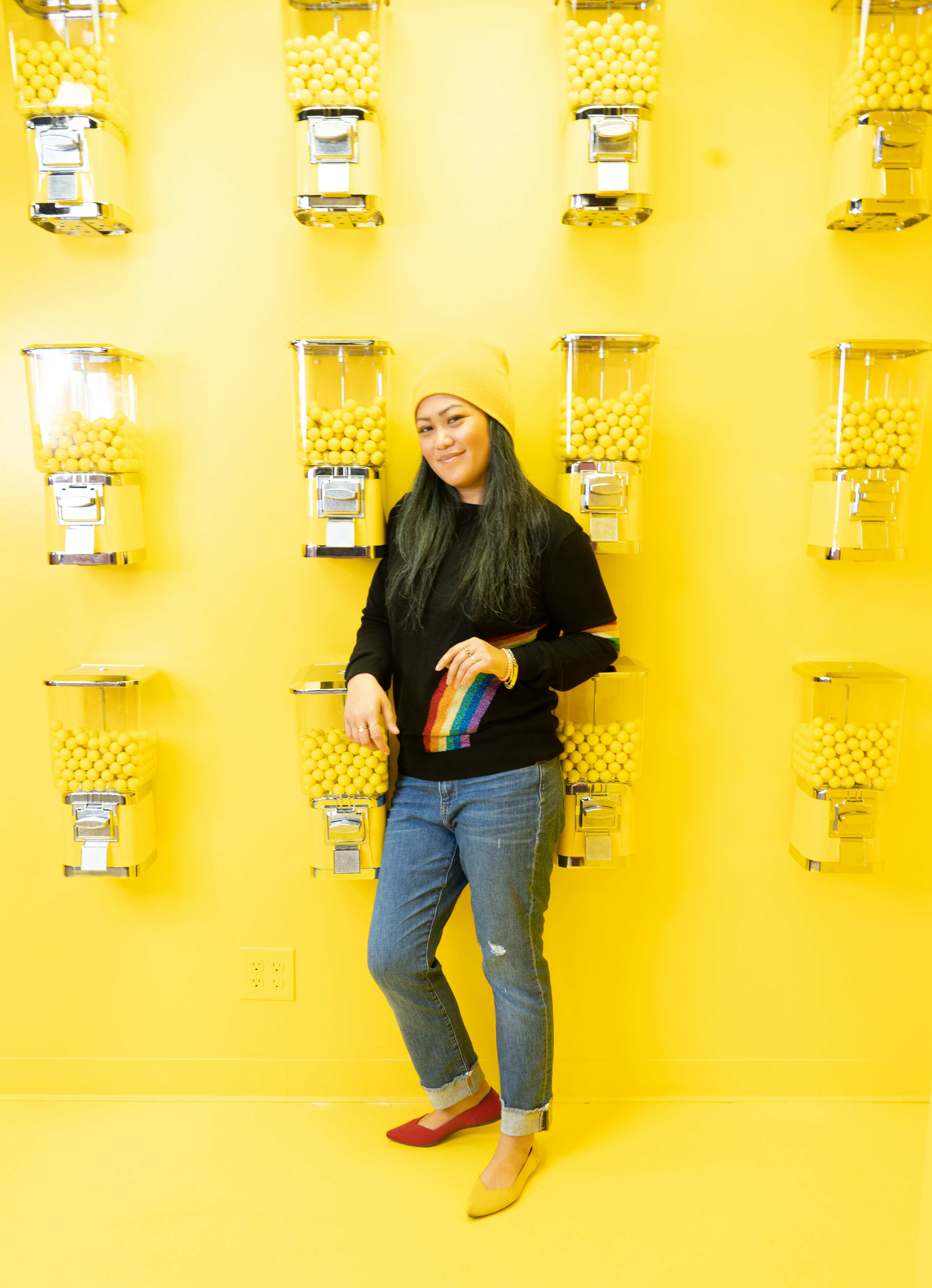 Wanita dengan kemeja lengan panjang hitam dan jeans denim biru memegang mug keramik putih dan hitam
