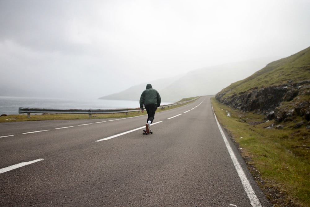 man in black jacket walking on gray asphalt road during daytime