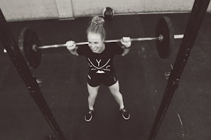 girl in red shirt and white panty holding red barbell
