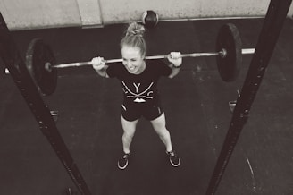 girl in red shirt and white panty holding red barbell