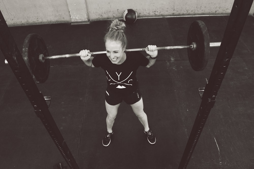 girl in red shirt and white panty holding red barbell