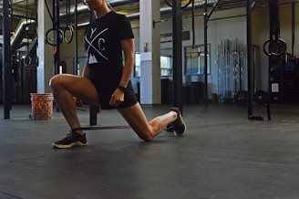 woman in black crew neck t-shirt and black shorts sitting on black metal bar