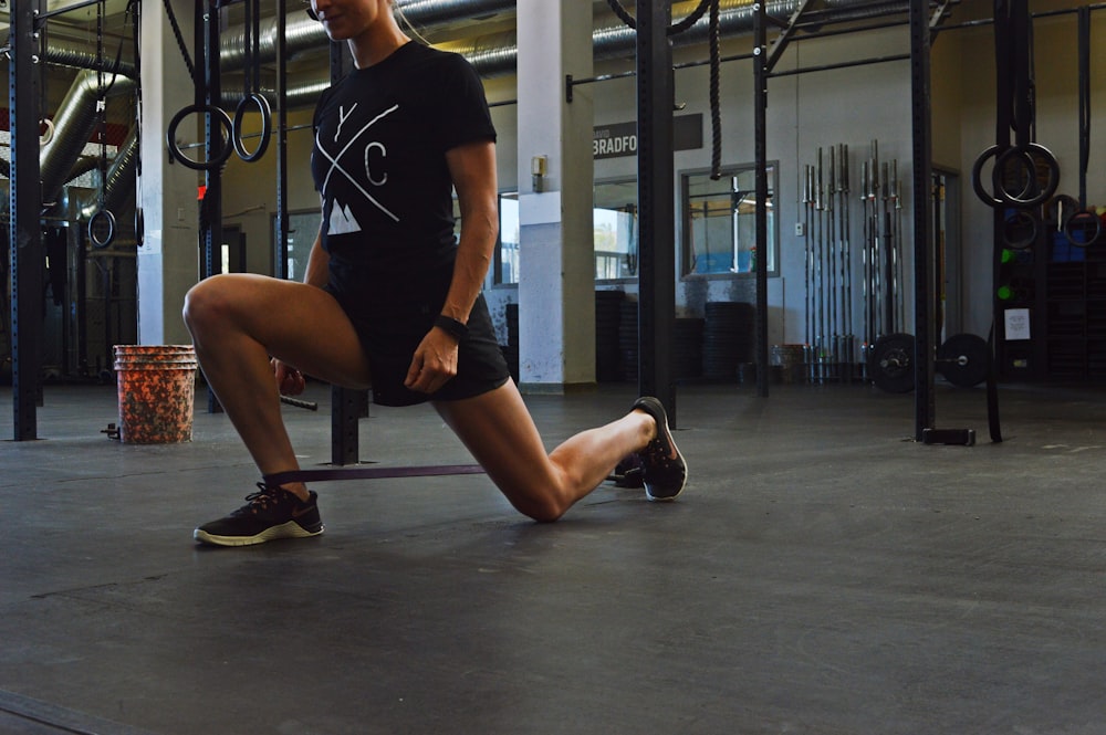 woman in black crew neck t-shirt and black shorts sitting on black metal bar