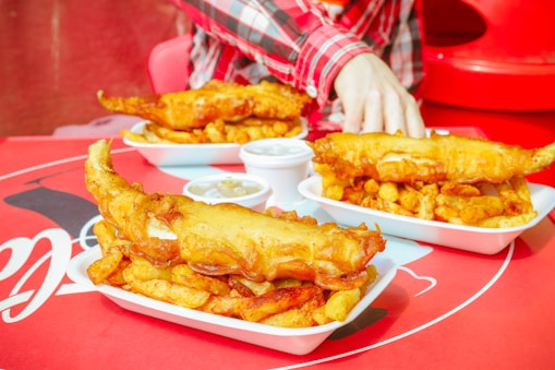 A close-up shot of golden crispy fish and thick hand-cut fries steaming on a paper tray.