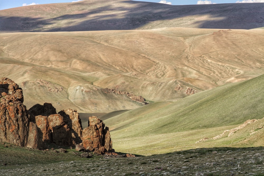 brown rock formation on green grass field during daytime