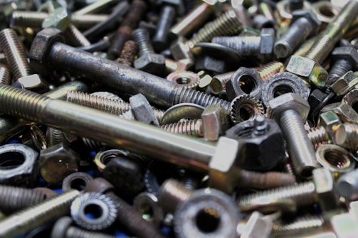 A stack of shiny steel nuts and bolts spilling from a small box.