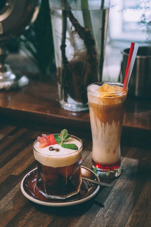 clear drinking glass with brown liquid on brown wooden table