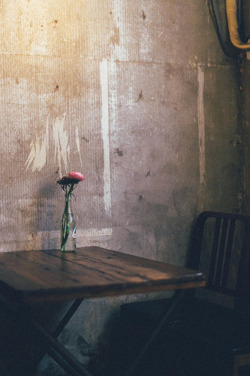 rosa roja en jarrón de vidrio transparente sobre mesa de madera marrón
