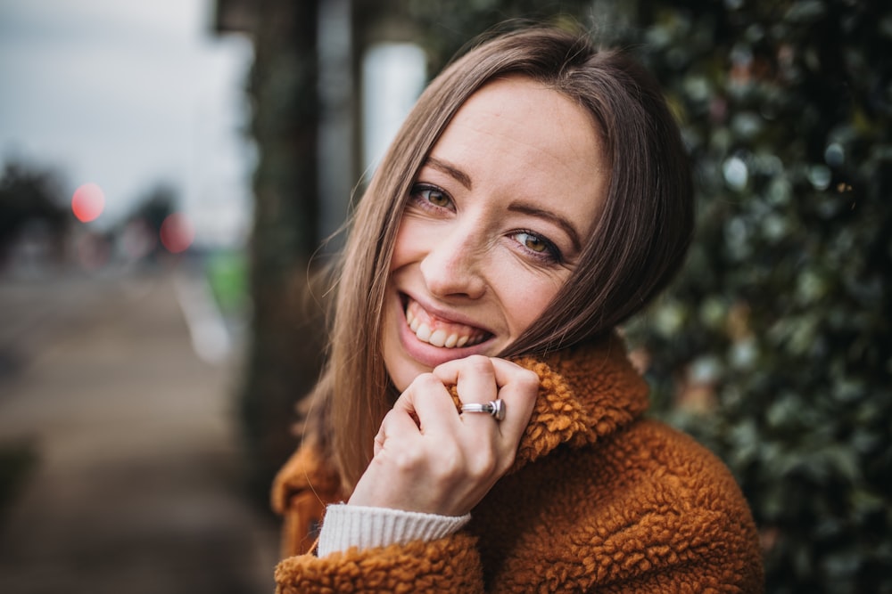 woman in brown coat holding white ceramic mug