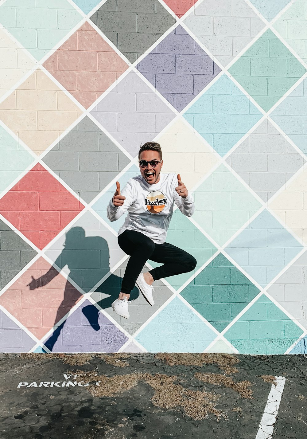 man in white and orange crew neck t-shirt and black pants sitting on blue and