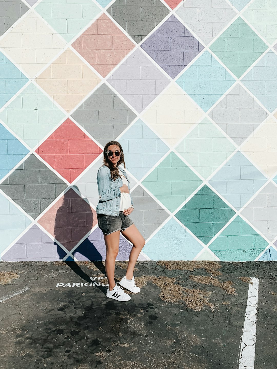woman in blue denim shorts standing beside blue and white wall