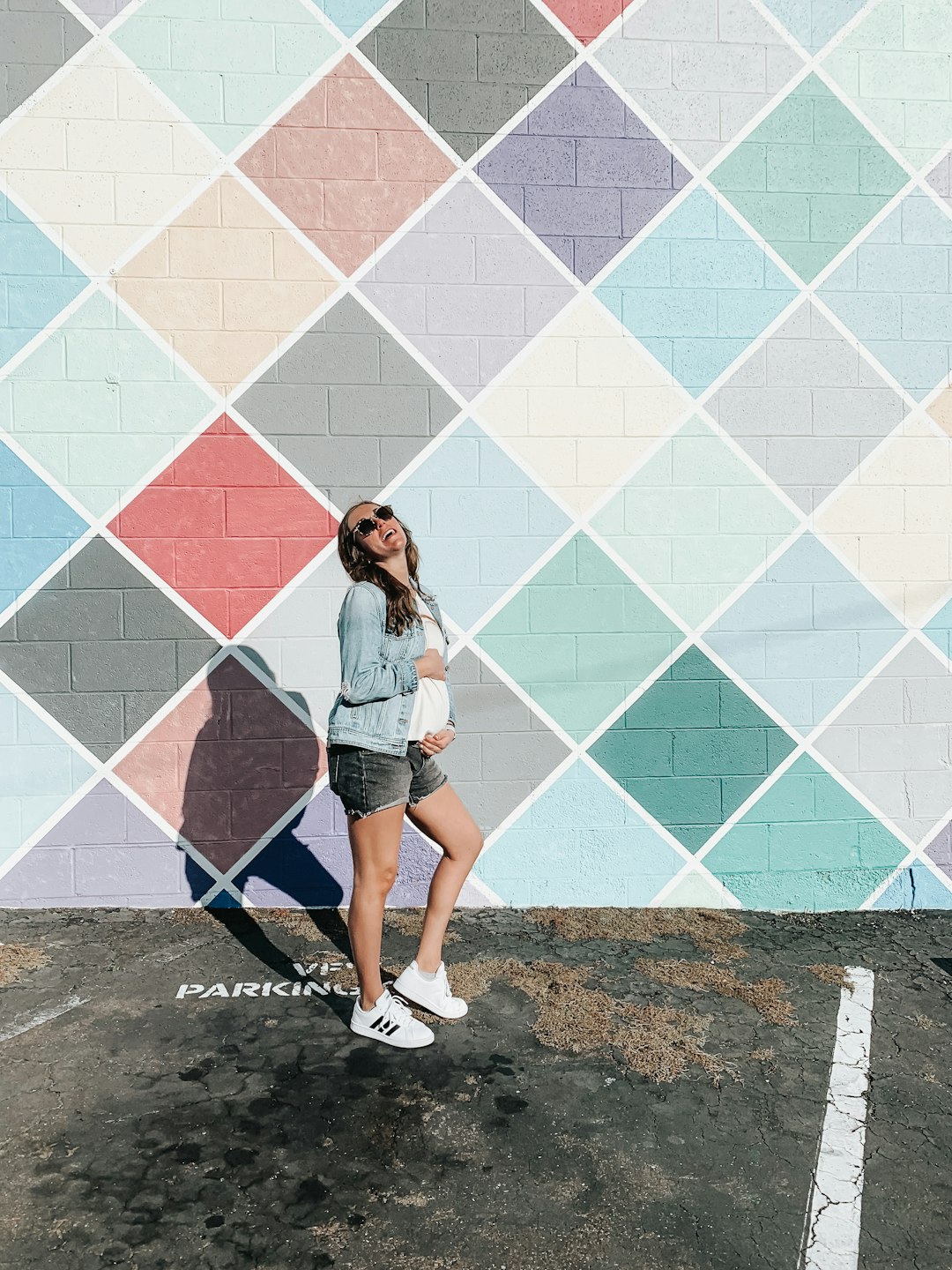 woman in blue denim shorts standing beside white blue and pink wall