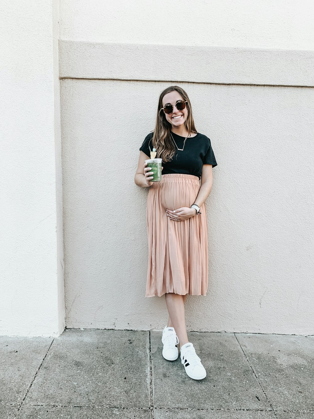 woman in black t-shirt and pink skirt standing beside wall