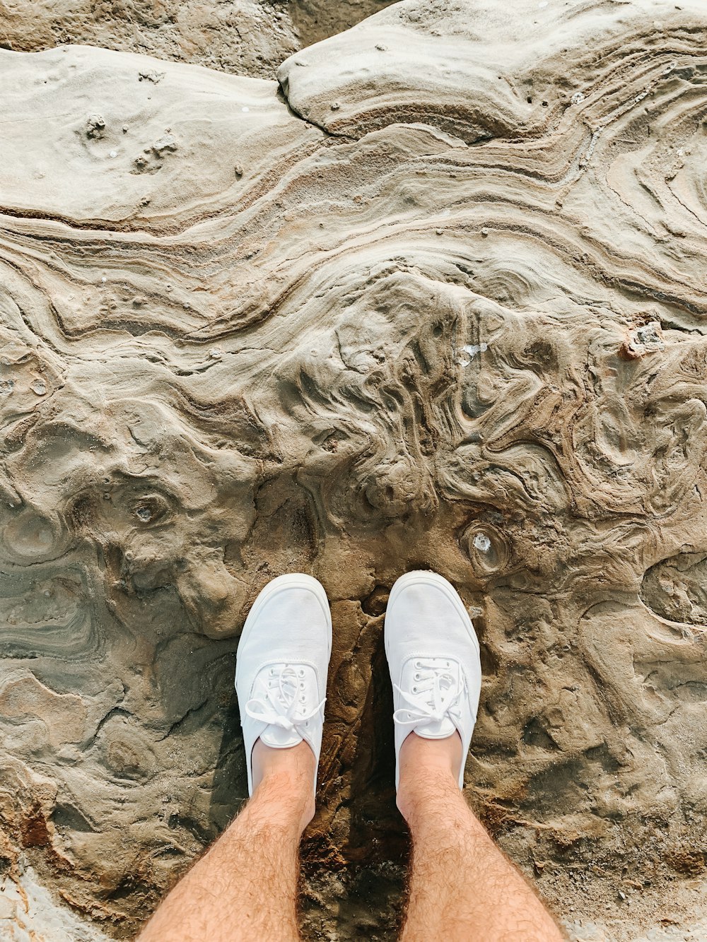 person in white shoes standing on gray rock