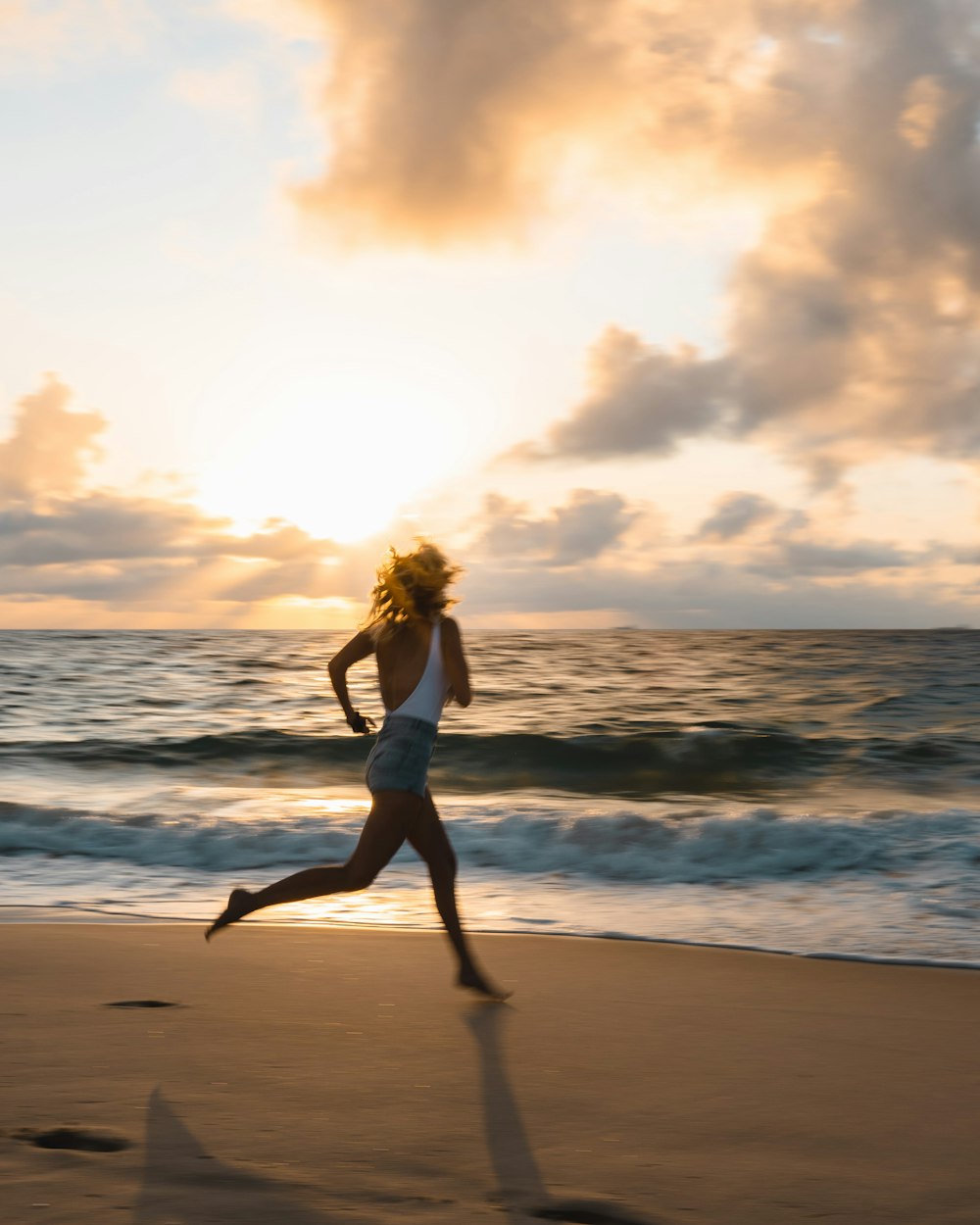 woman in white bikini standing on beach during sunset