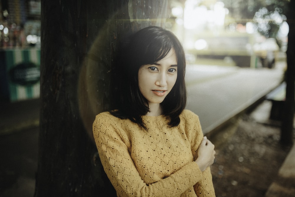 girl in yellow sweater standing beside glass wall