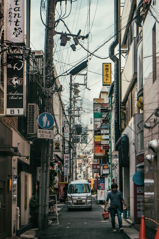 cars on road in between buildings during daytime in Sannomiya Japan