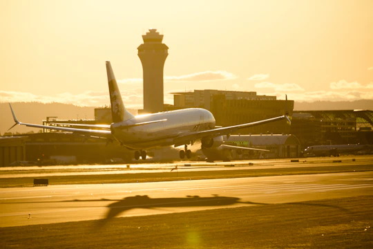 A sleek aircraft taxiing on a runway at sunset with control tower in the background.