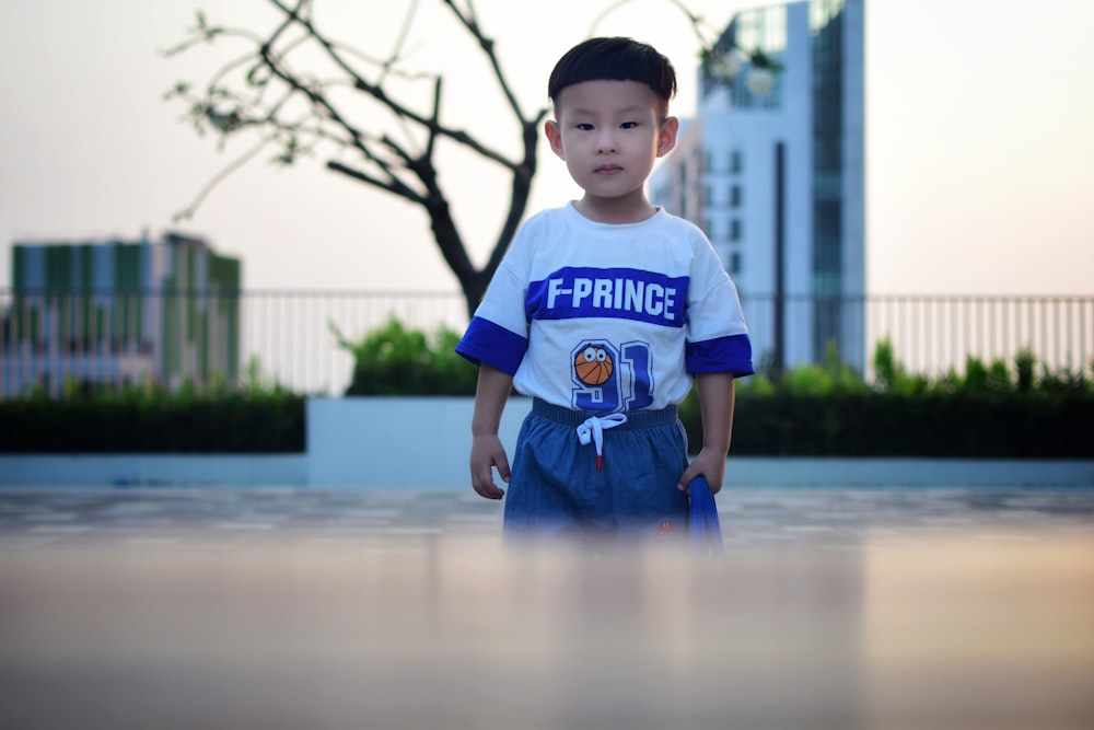 menino em azul e branco t-shirt pescoço da tripulação em pé na água durante o dia