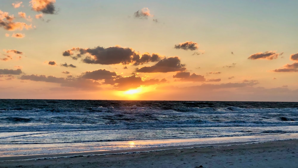 sea waves crashing on shore during sunset