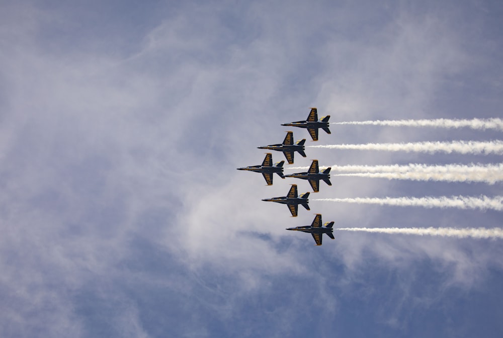 Quatre avions de chasse en plein vol sous des nuages blancs pendant la journée