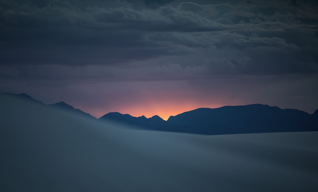the sun is setting over the mountains in the distance,