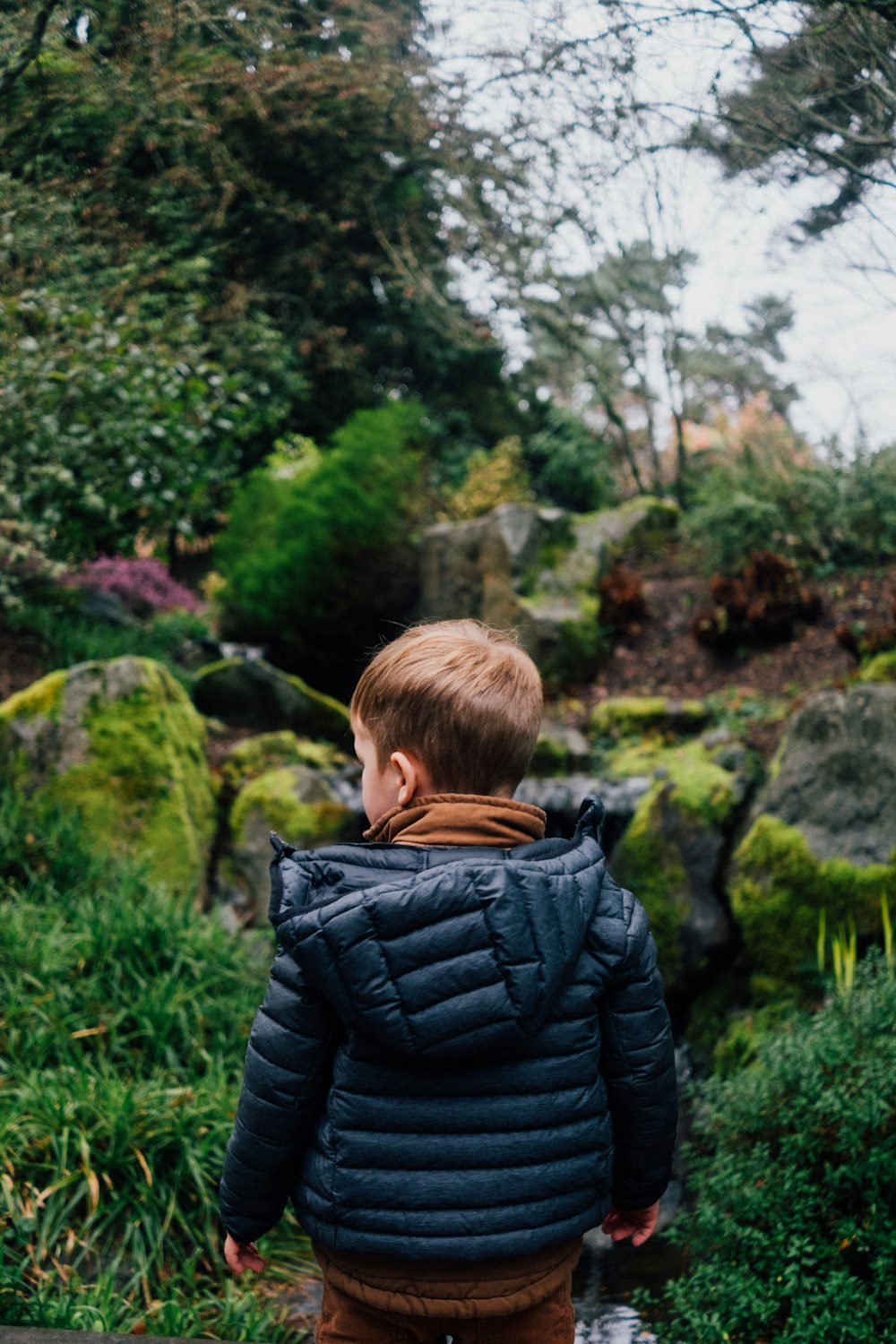 boy in black bubble jacket standing on green grass field during daytime