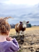 a little girl standing in front of a cow