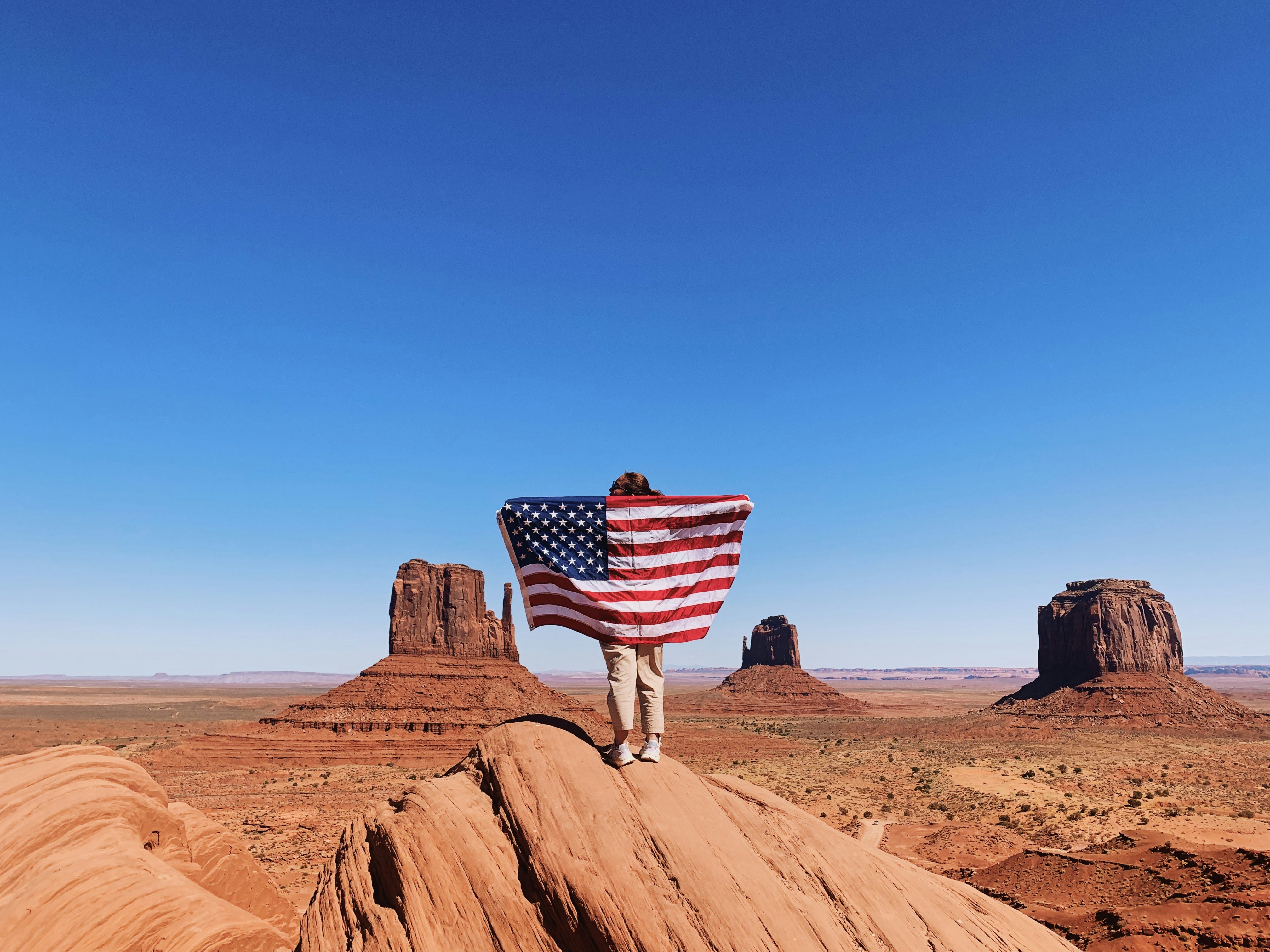us a flag on brown rock formation under blue sky during daytime