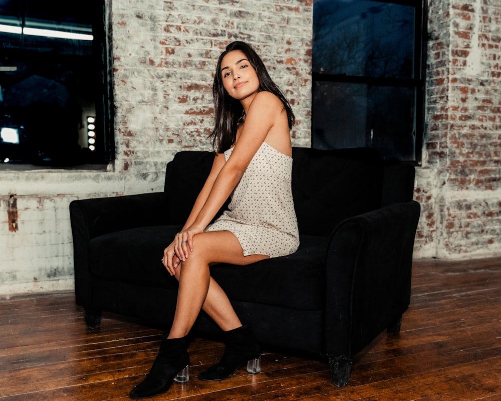 woman in black and white polka dots dress sitting on black sofa