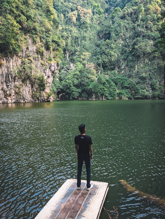 man in black jacket standing on white wooden dock near body of water during daytime in Ipoh Malaysia