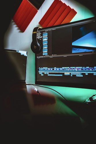 A video editor reviewing footage on a multi-monitor setup in a dim studio