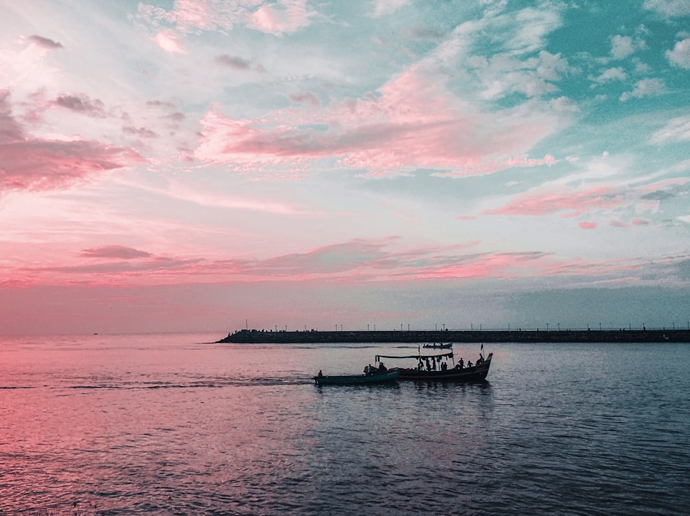 white and black boat on sea under blue and white cloudy sky during daytime