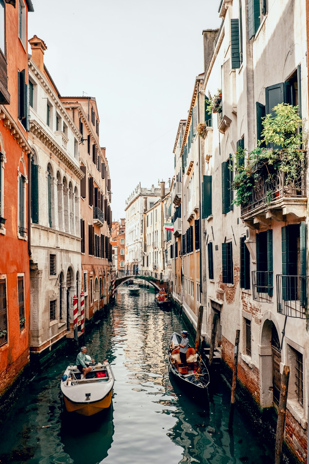 people riding on boat on river between concrete buildings during daytime